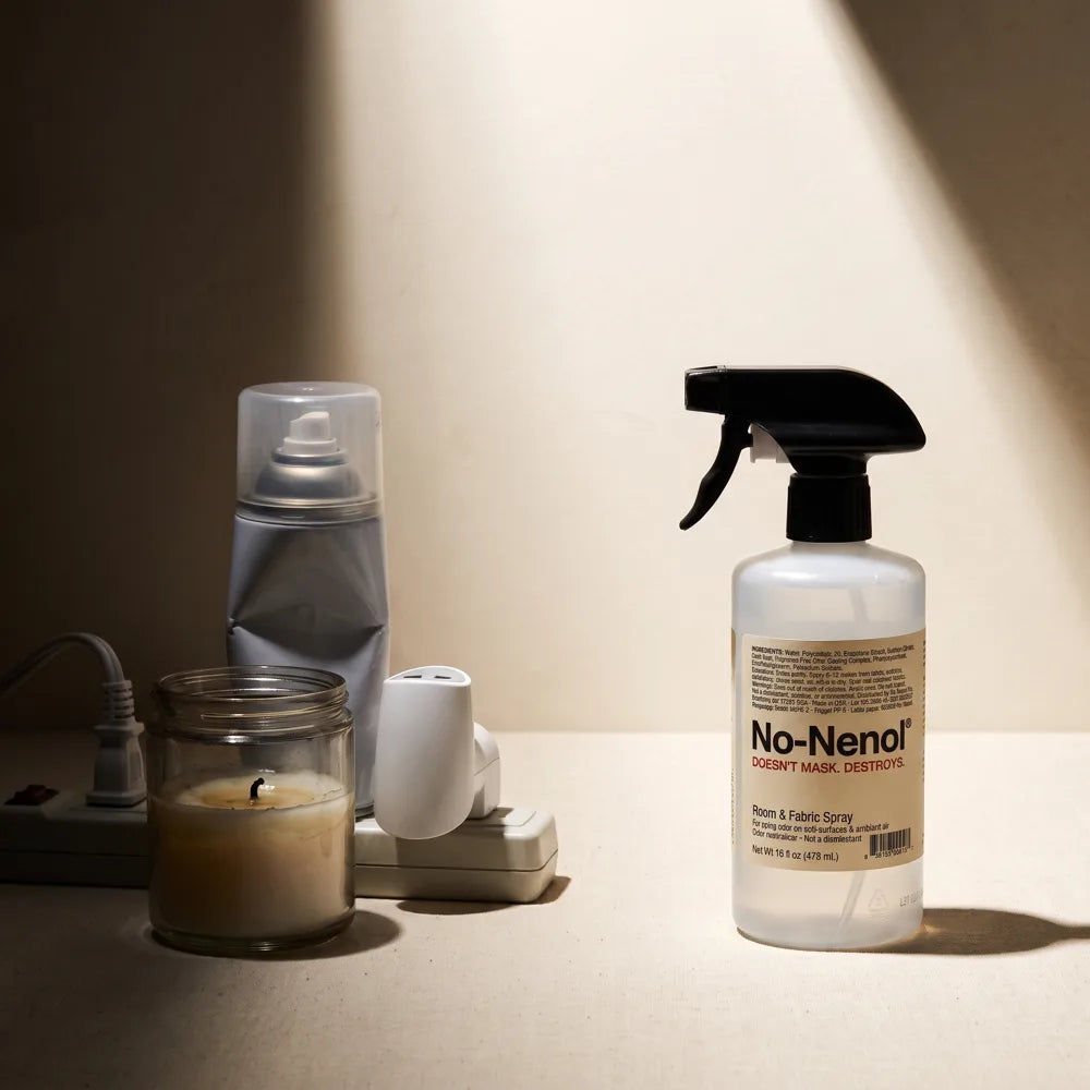 A spent candle and air fresheners in shadow beside the No-Nenol spray in light